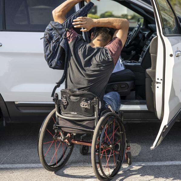 Un enfant en situation de handicap moteur met son sac à dos pour aller en classe