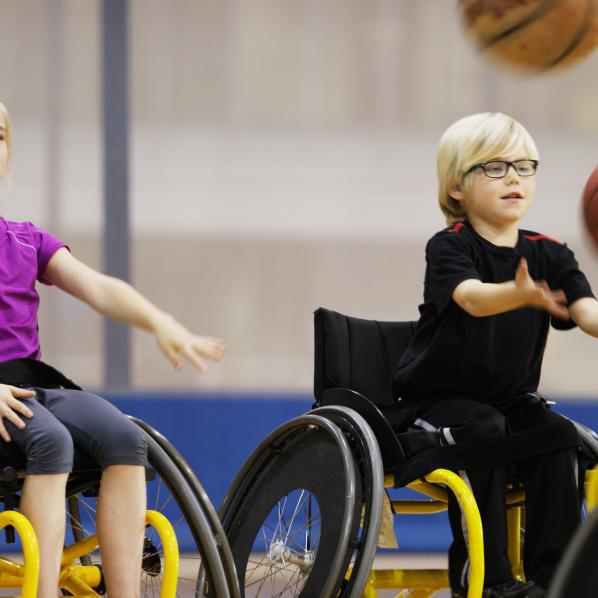 Deux enfants pratiquent du handisport dans un gymnase