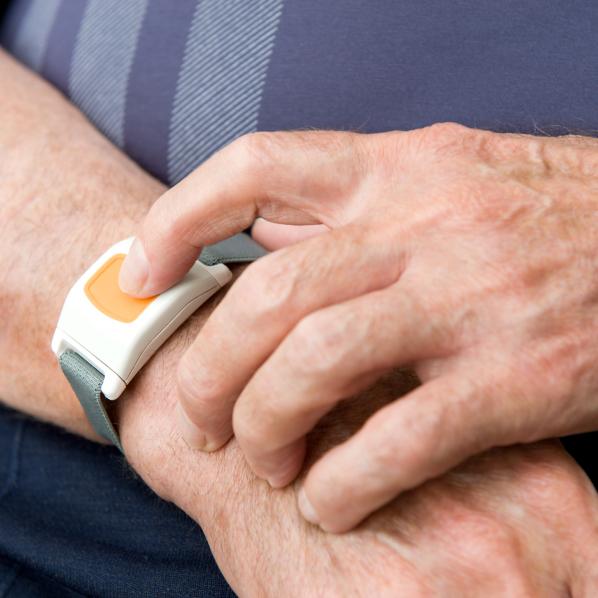 Une personne porte à son poignet un dispositif de téléassistance sous forme de montre permettant d'appeler les secours en cas d'urgence