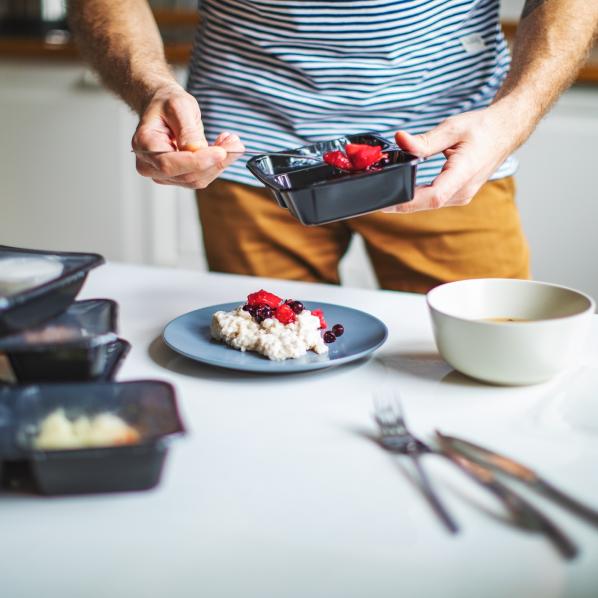 Un jeune homme a reçu son portage de repas pour les trois prochains jours. Il verse sa nourriture dans une assiette.