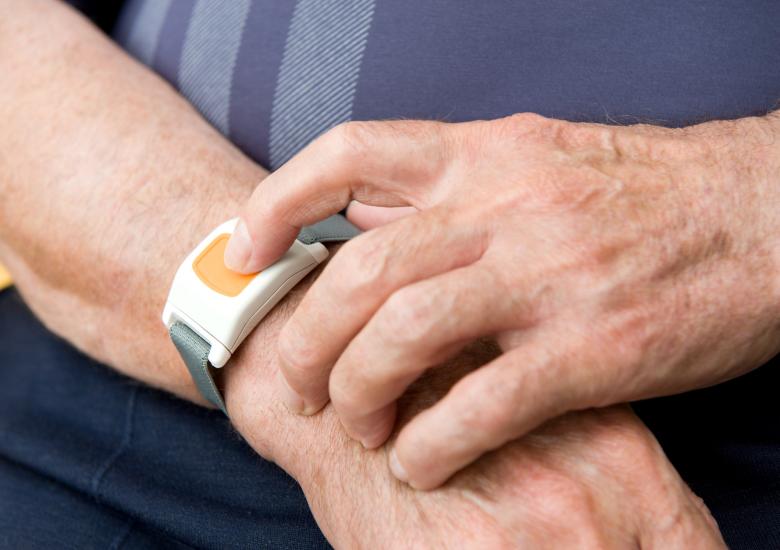 Une personne porte à son poignet un dispositif de téléassistance sous forme de montre permettant d'appeler les secours en cas d'urgence