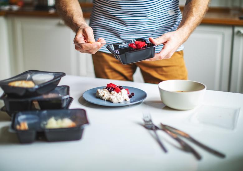 Un jeune homme a reçu son portage de repas pour les trois prochains jours. Il verse sa nourriture dans une assiette.