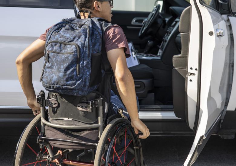Un étudiant en fauteuil roulant monte à bord d'une voiture.